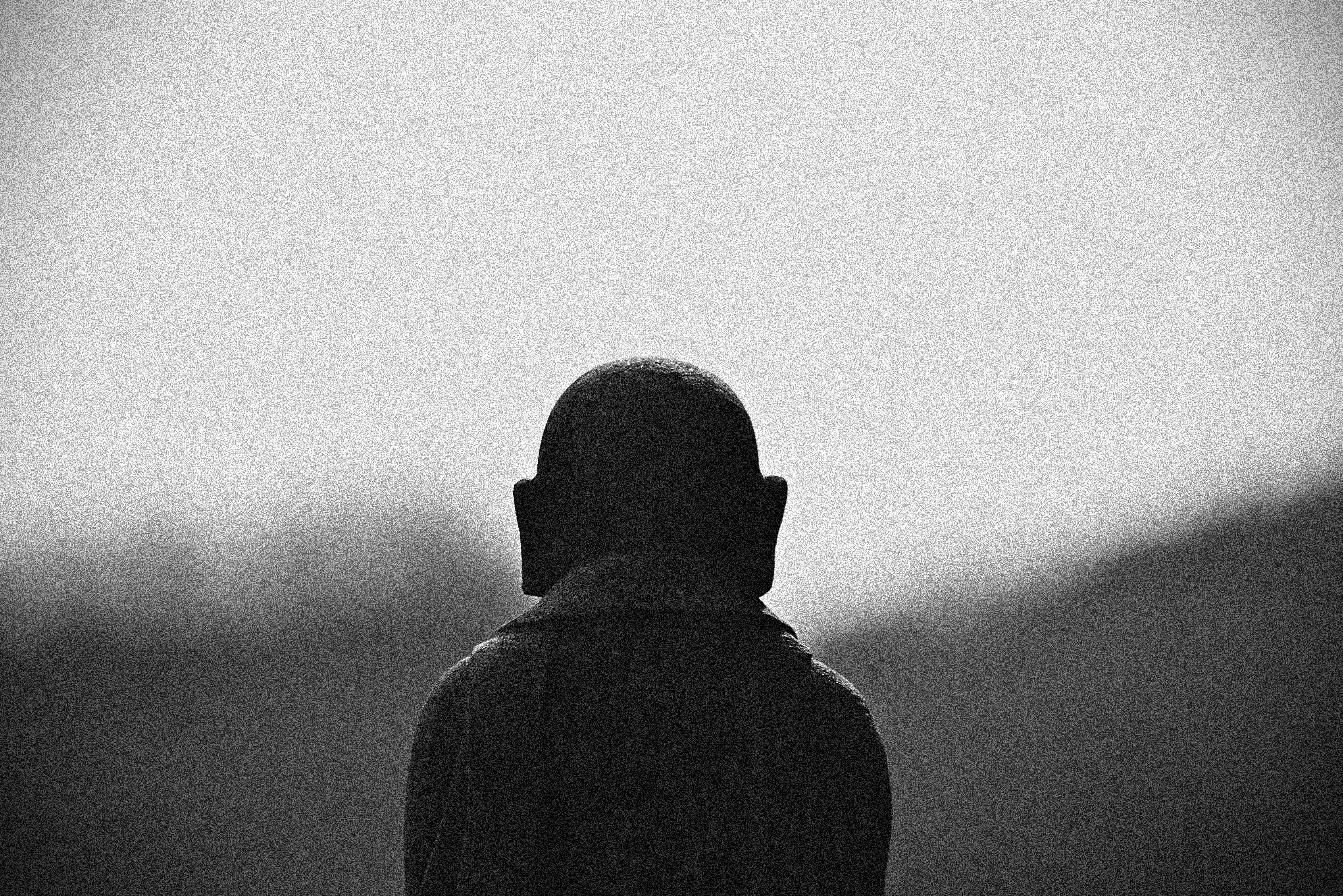 a black and white photo of a person with a bird on his head