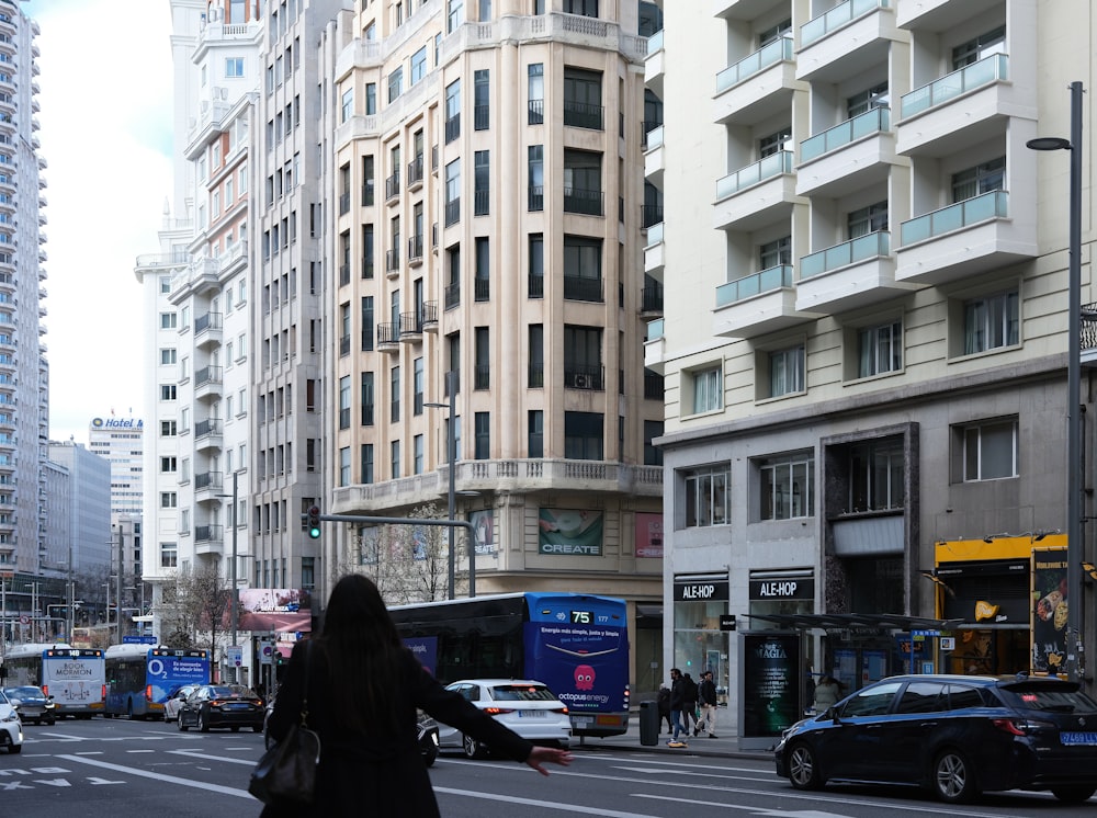 a woman crossing the street in front of tall buildings