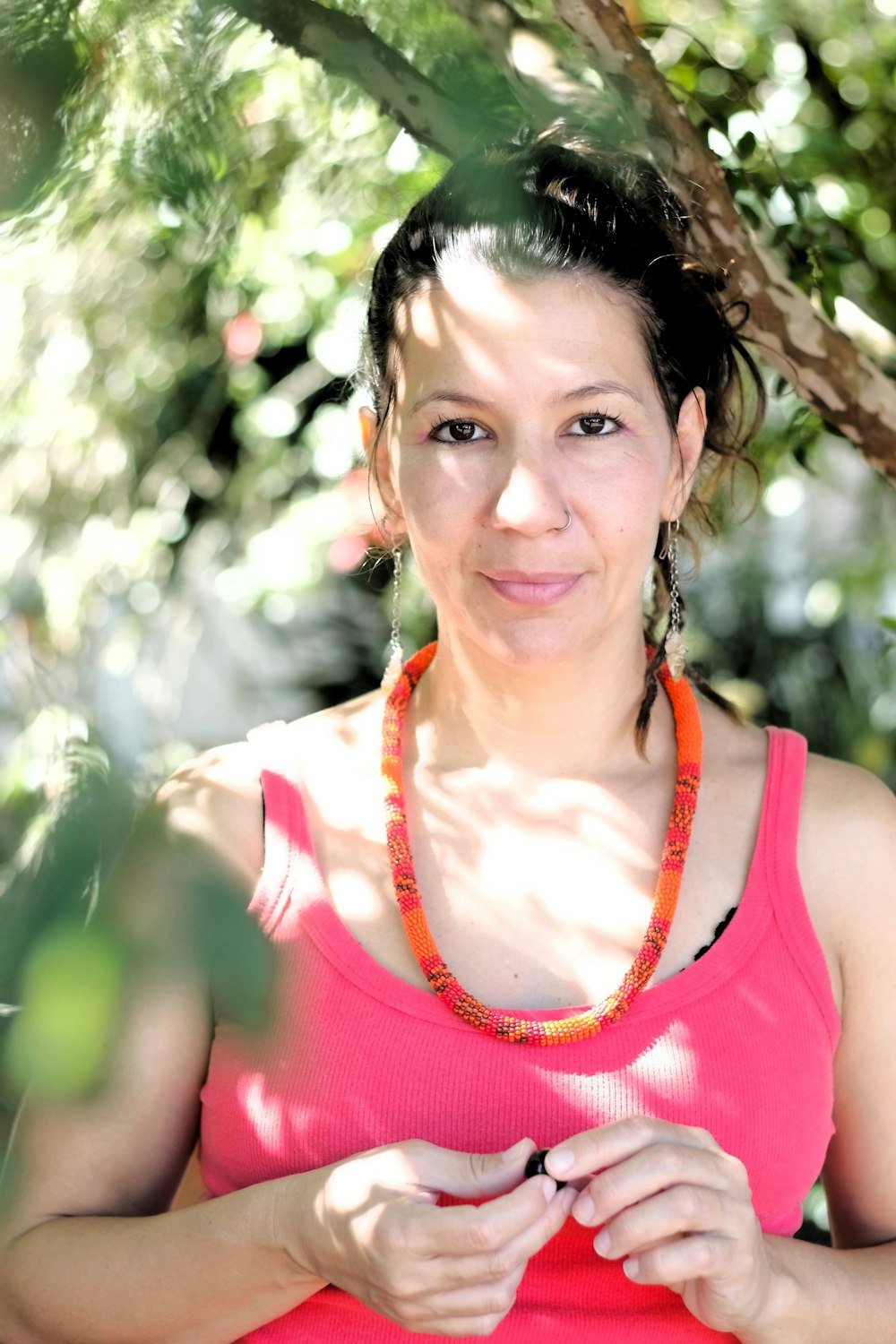 a woman standing under a tree wearing a necklace