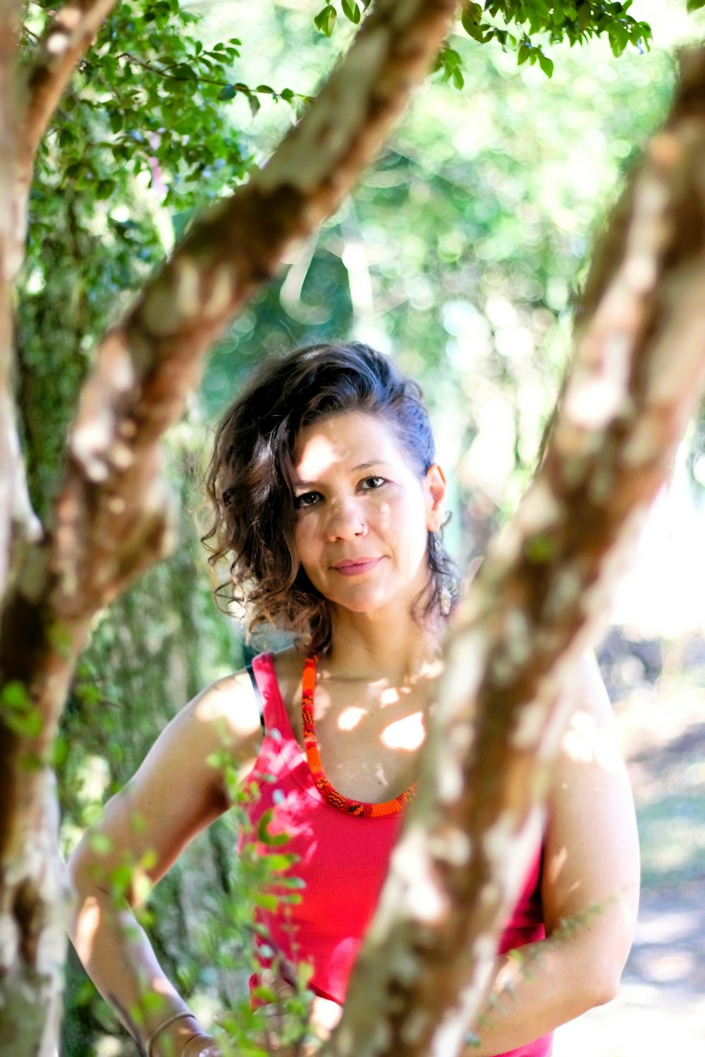 a woman in a red dress standing next to a tree