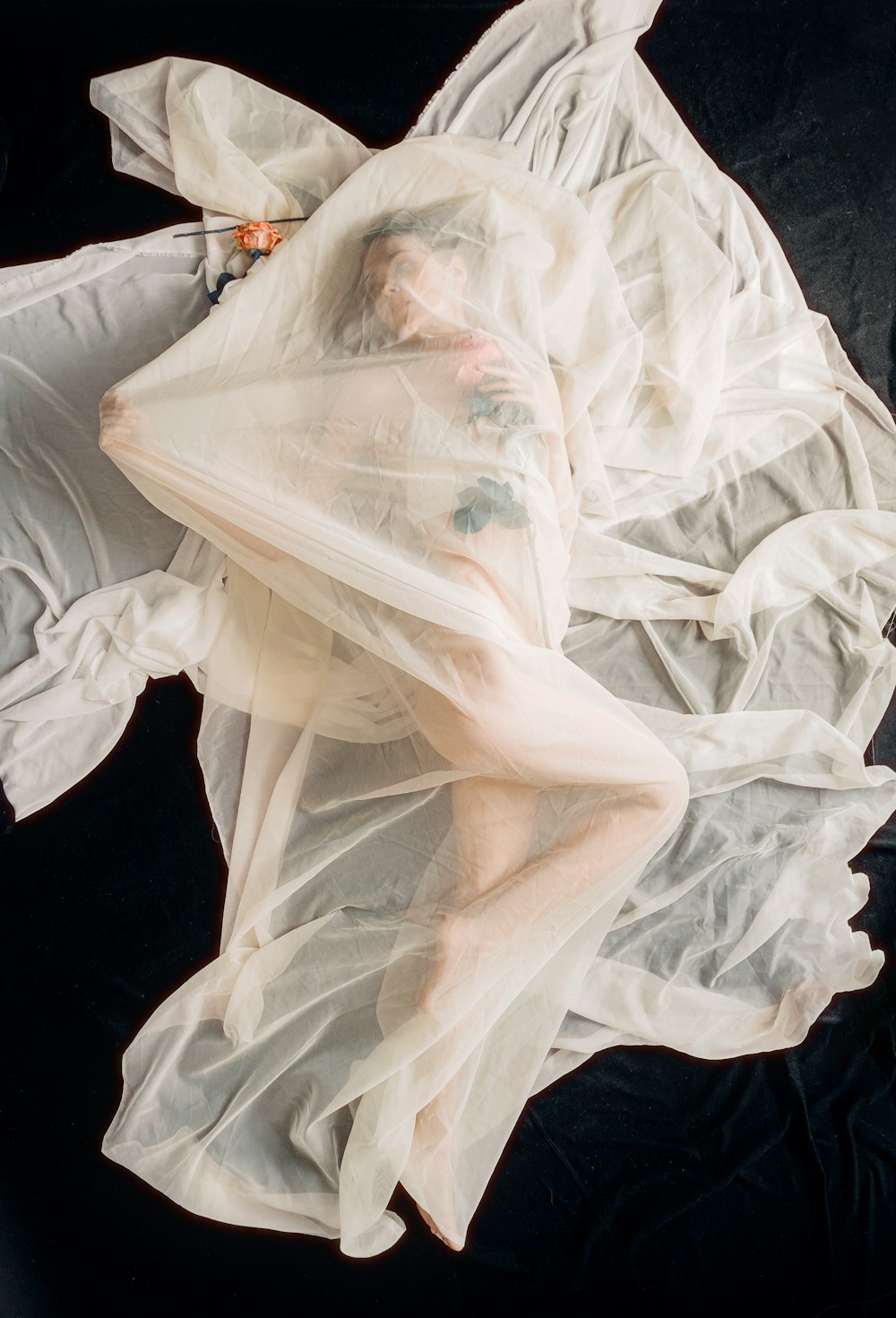 a woman laying on top of a white sheet