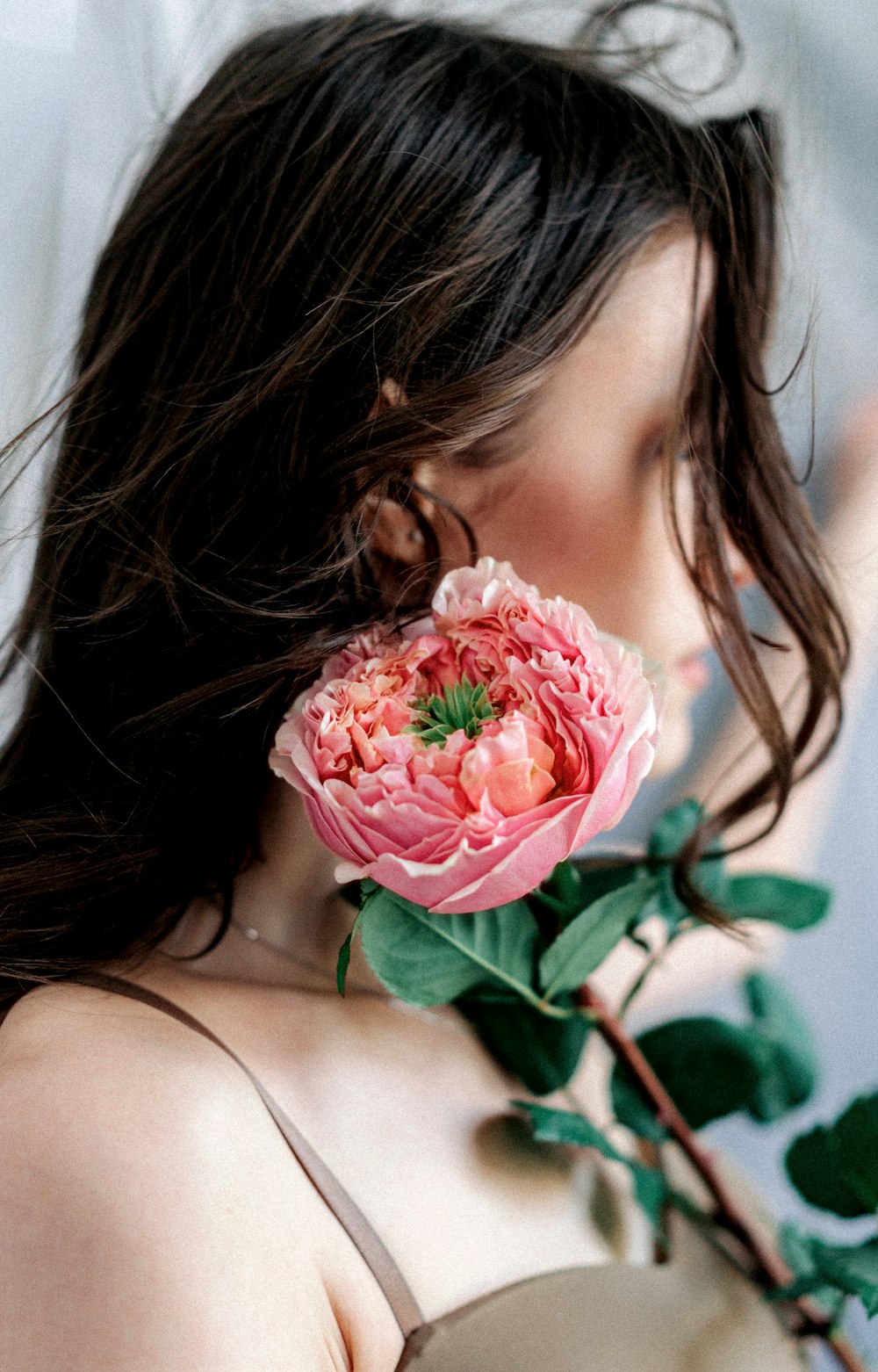 a woman holding a pink flower in her hand