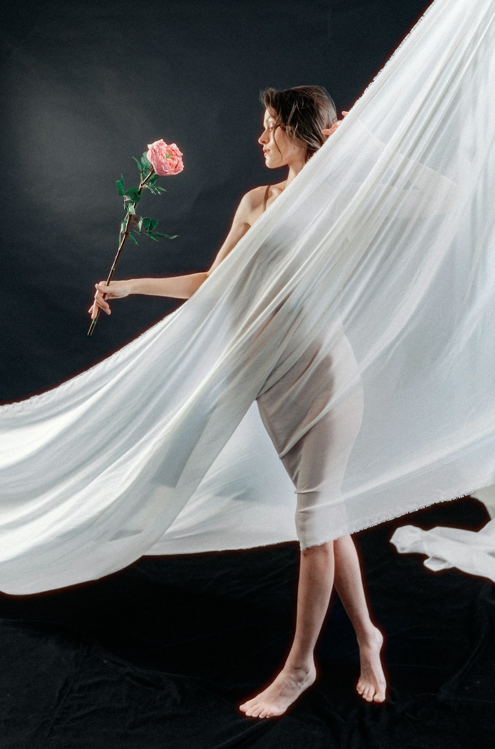 a woman in a white dress holding a rose