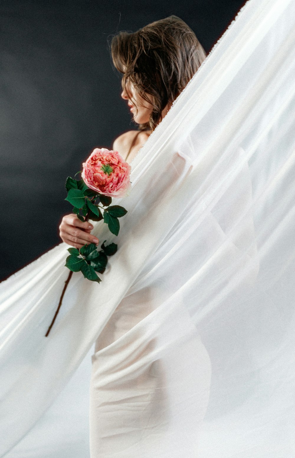 a woman in a white dress holding a rose