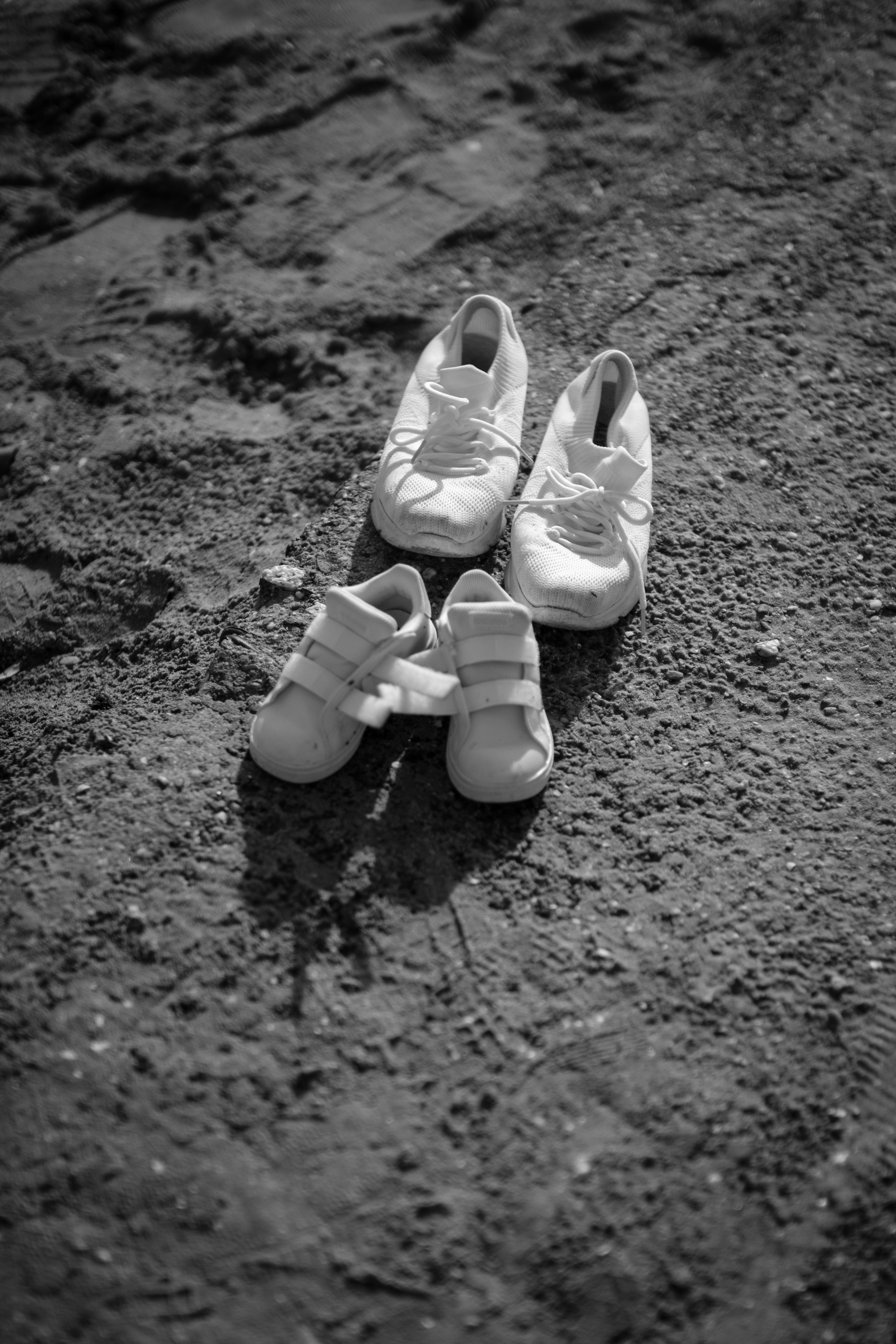 a pair of white shoes sitting on top of a dirt field