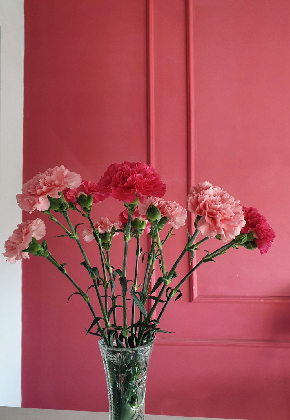 eine Vase gefüllt mit rosa Blumen auf einem Tisch