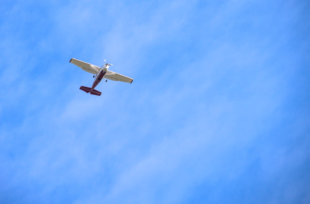 a small airplane flying through a blue sky