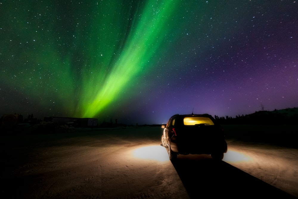 a car parked in the middle of a road under a green and purple sky