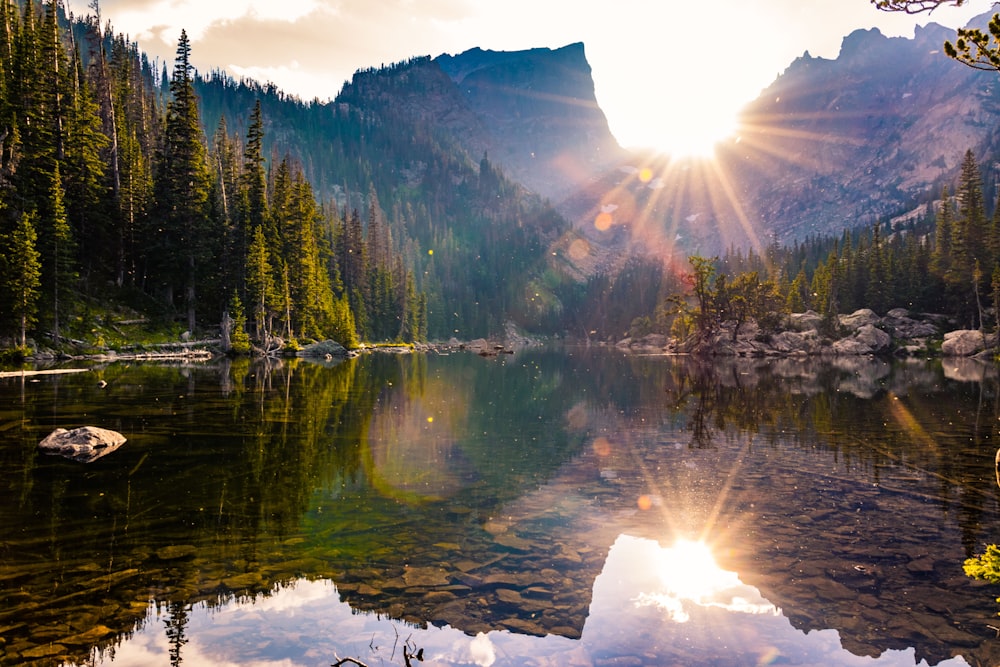 the sun is shining over a mountain lake