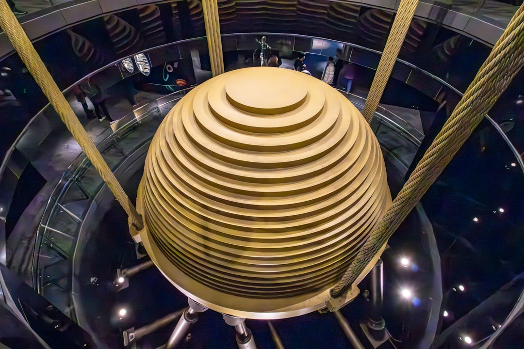 a very tall building with a very large round structure, This picture captures the impressive tuned mass damper inside Taipei 101, one of the world
