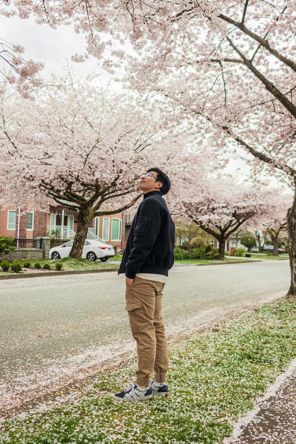 a man standing on the side of a road next to a tree