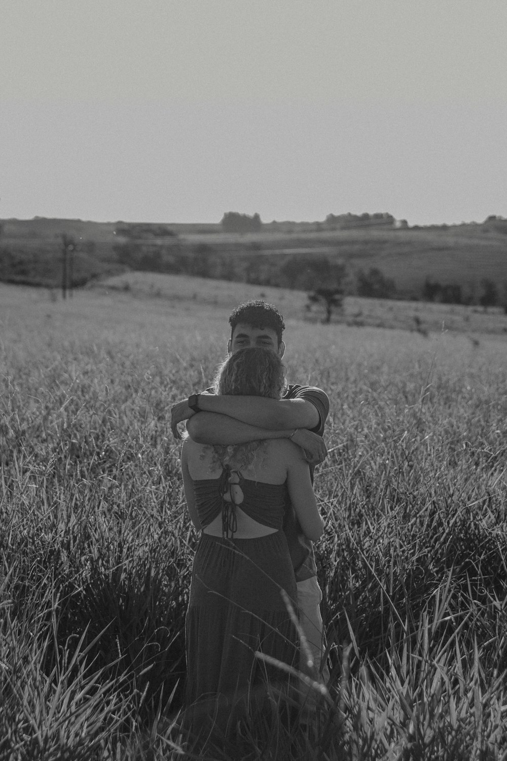 a man holding a woman in a field of tall grass