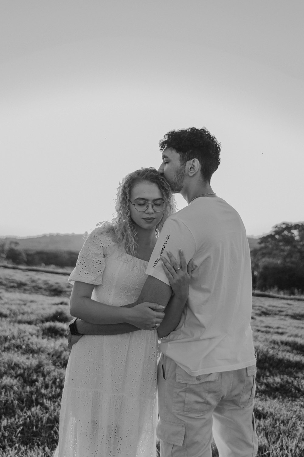 a black and white photo of a man kissing a woman