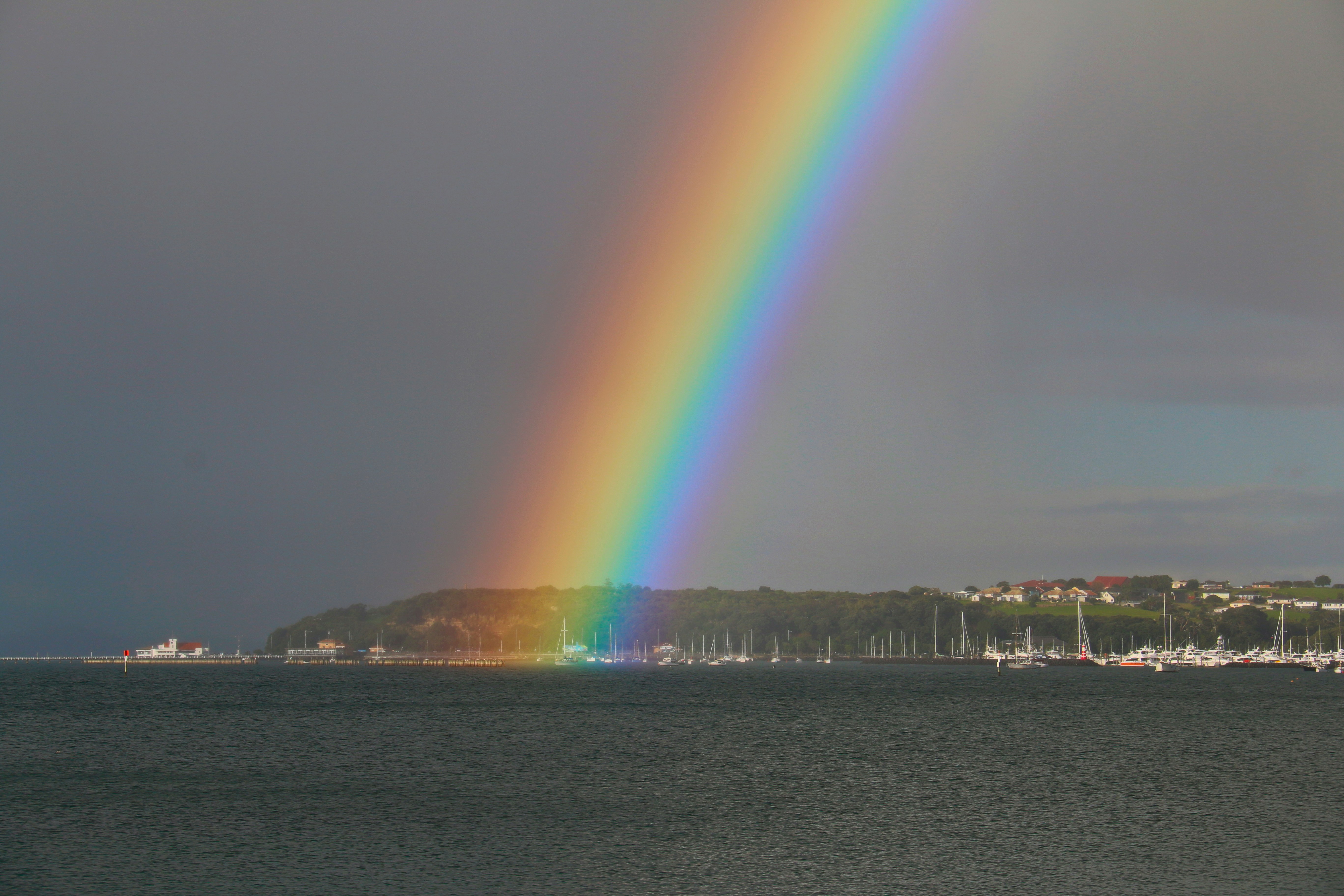 a rainbow in the sky over a body of water, 