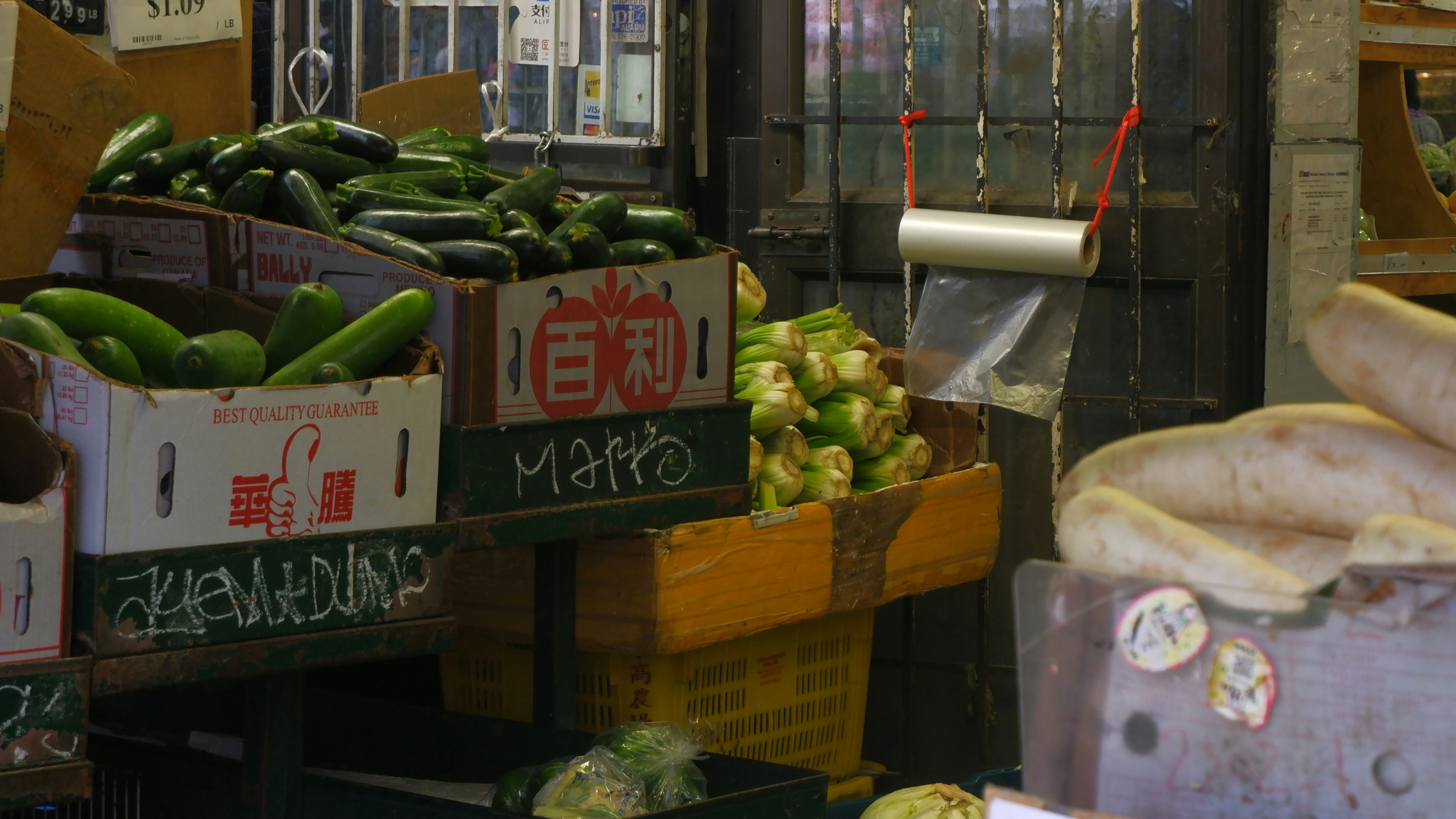 a fruit and vegetable stand with bananas, cucumbers, and other produce, Market