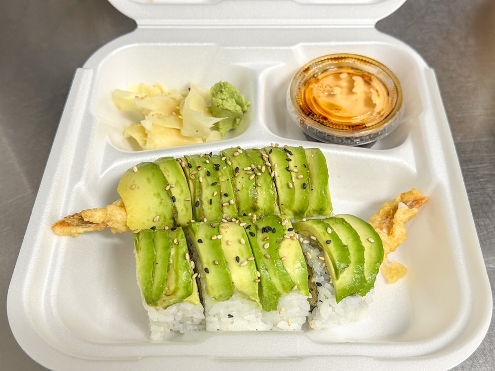 a plastic container filled with sushi and vegetables