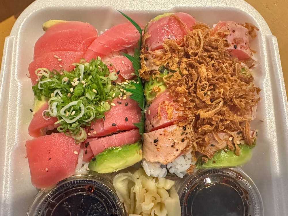 a plastic container filled with sushi and sauces