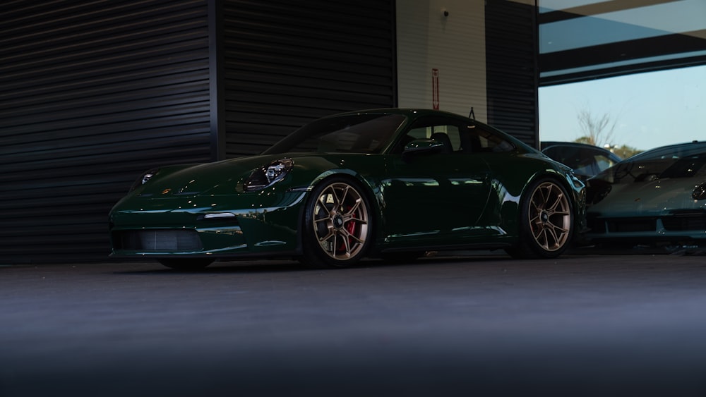 a green sports car parked in front of a garage