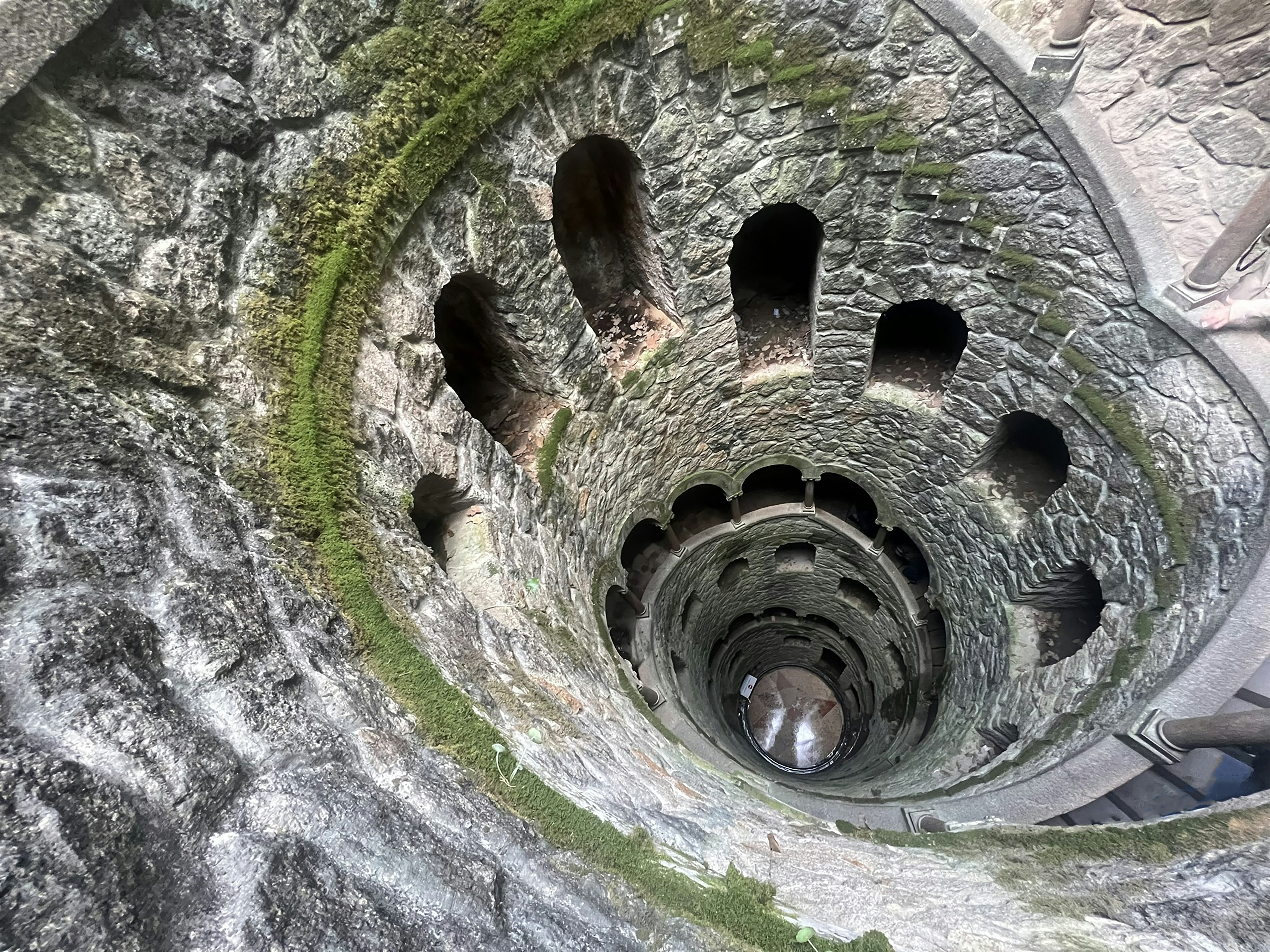 a spiral stone staircase with moss growing on it