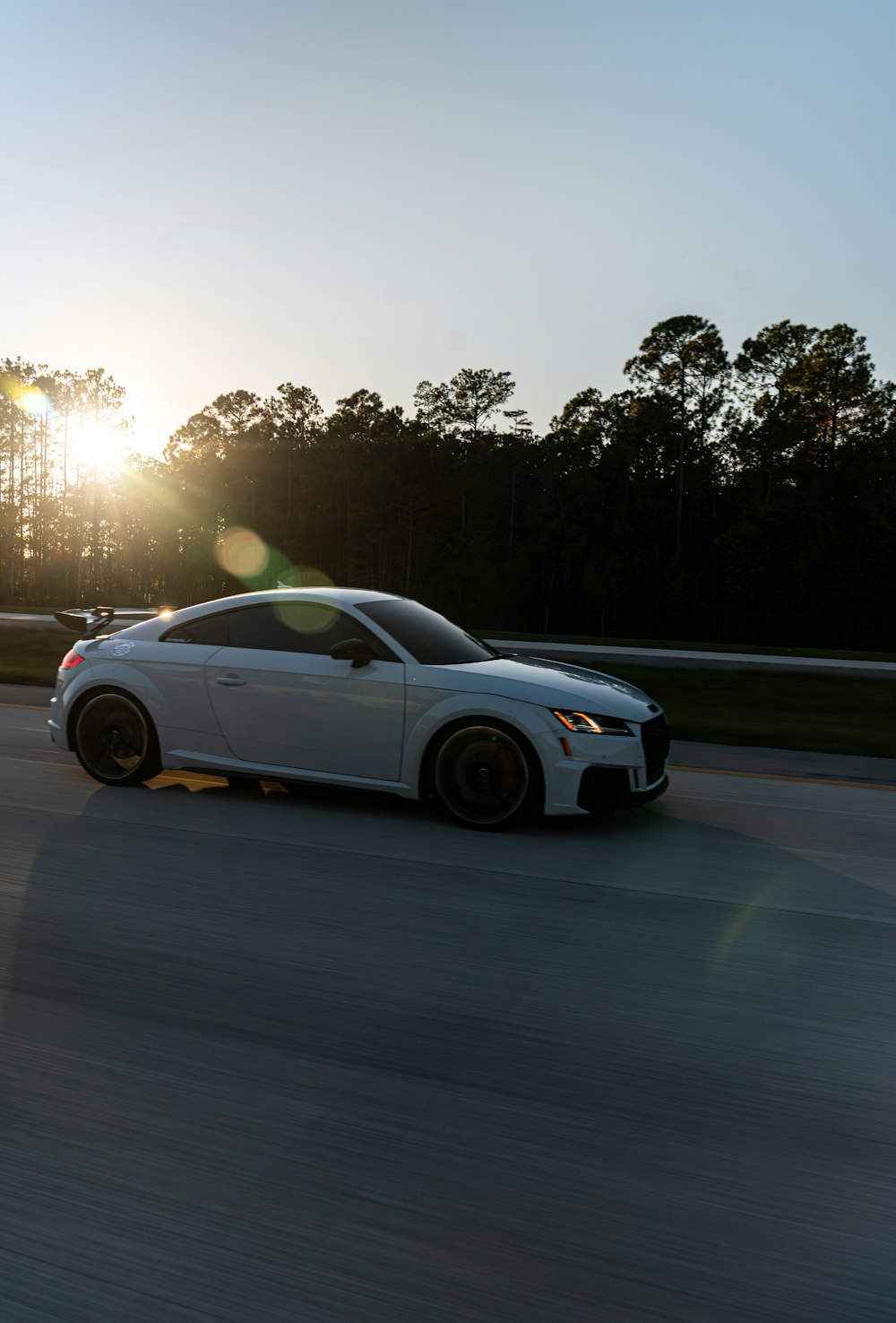 a white sports car driving down a road