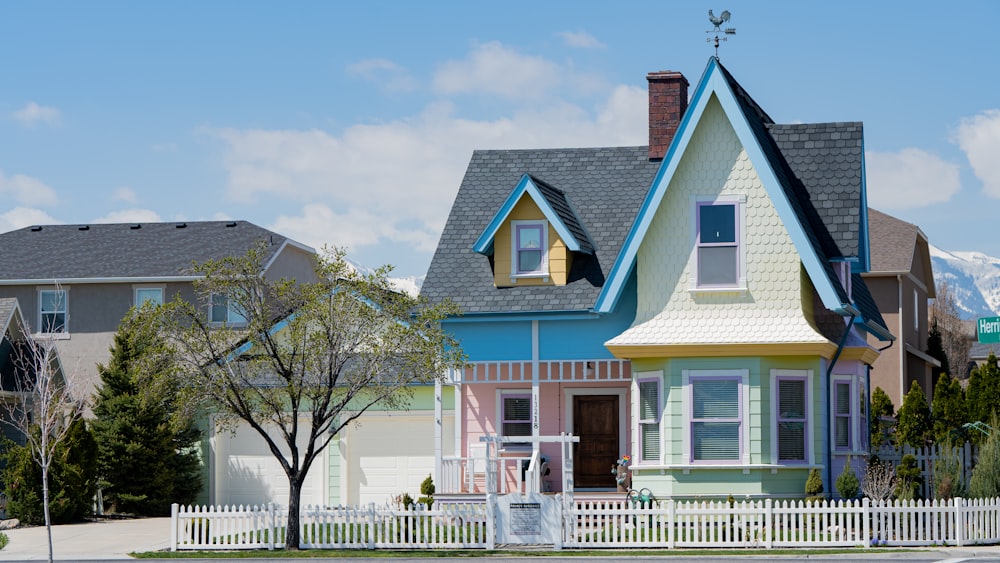 a multicolored house with a white picket fence