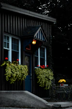 a small house with flowers in the window boxes