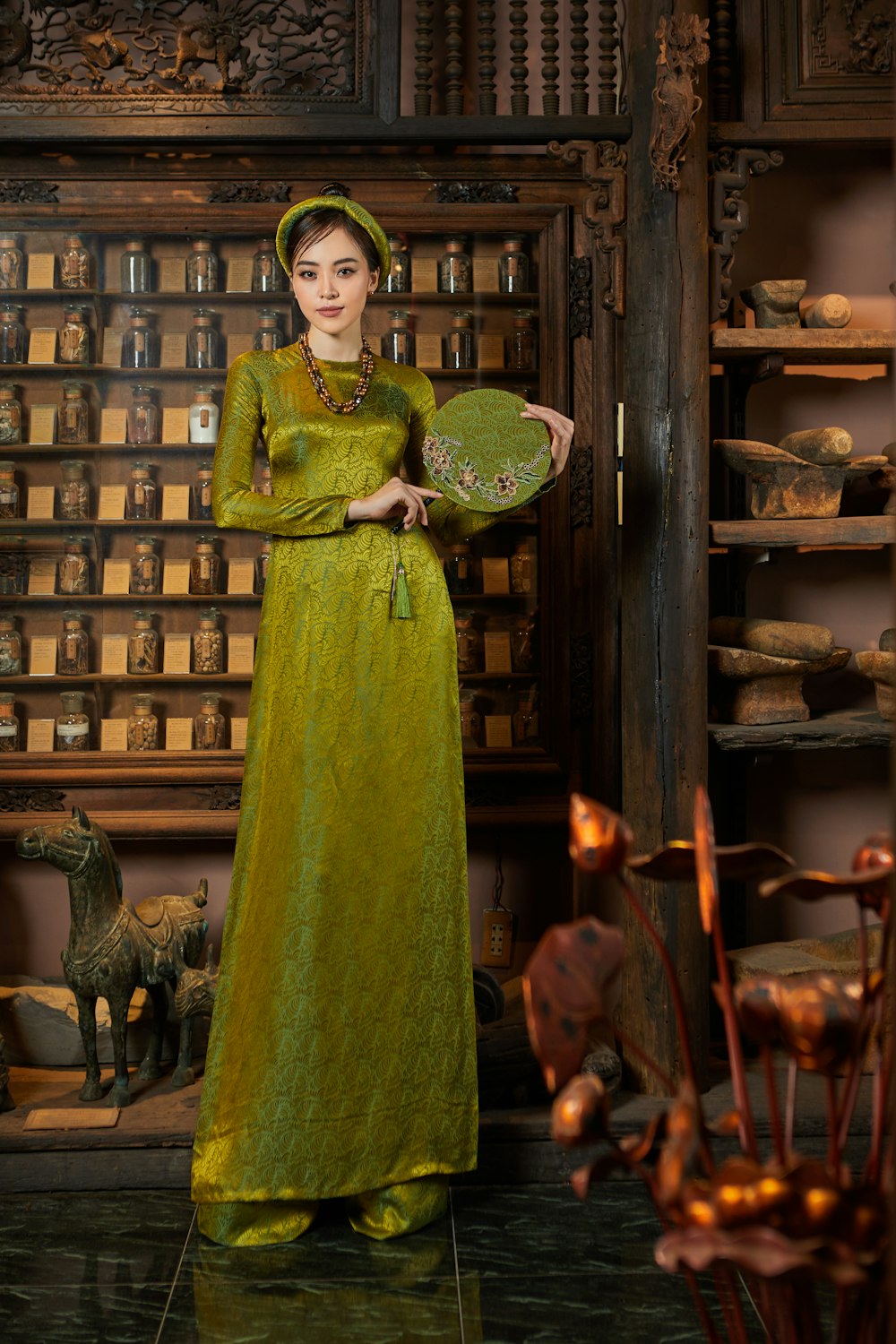 a woman in a green dress holding a fan