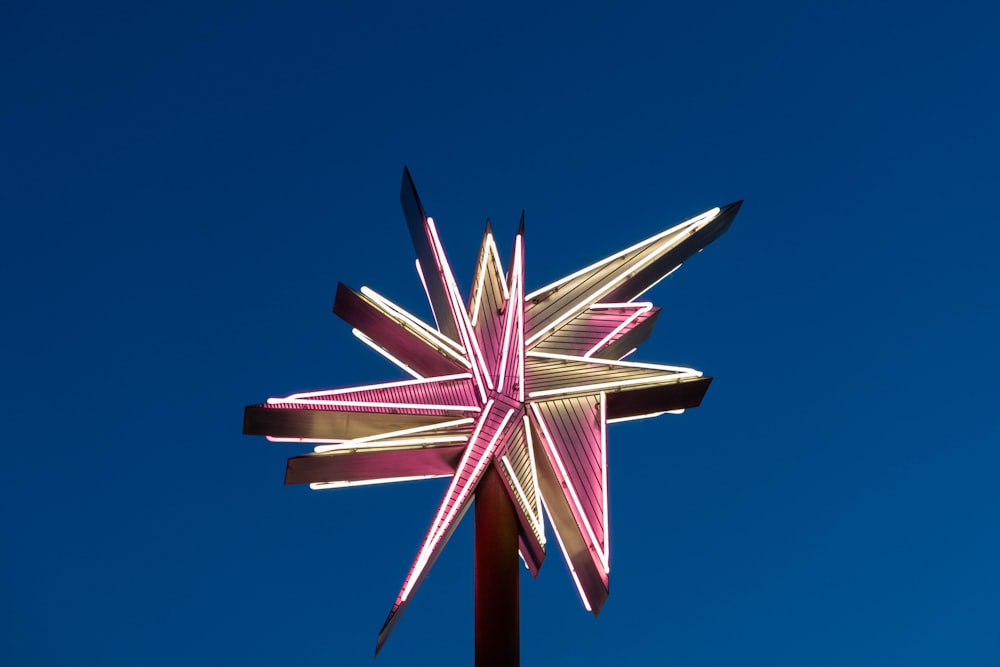une étoile rose et blanche au sommet d’un poteau