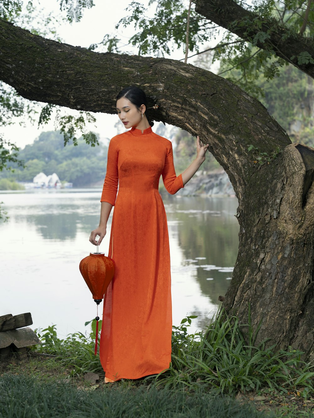 a woman in an orange dress standing next to a tree