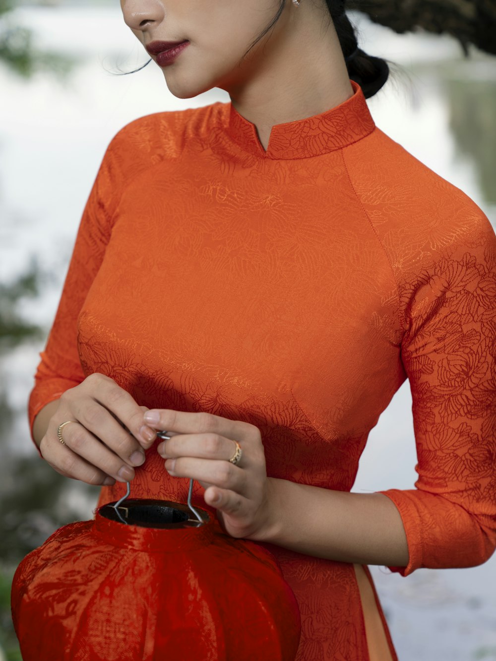 a woman in an orange dress holding a red purse