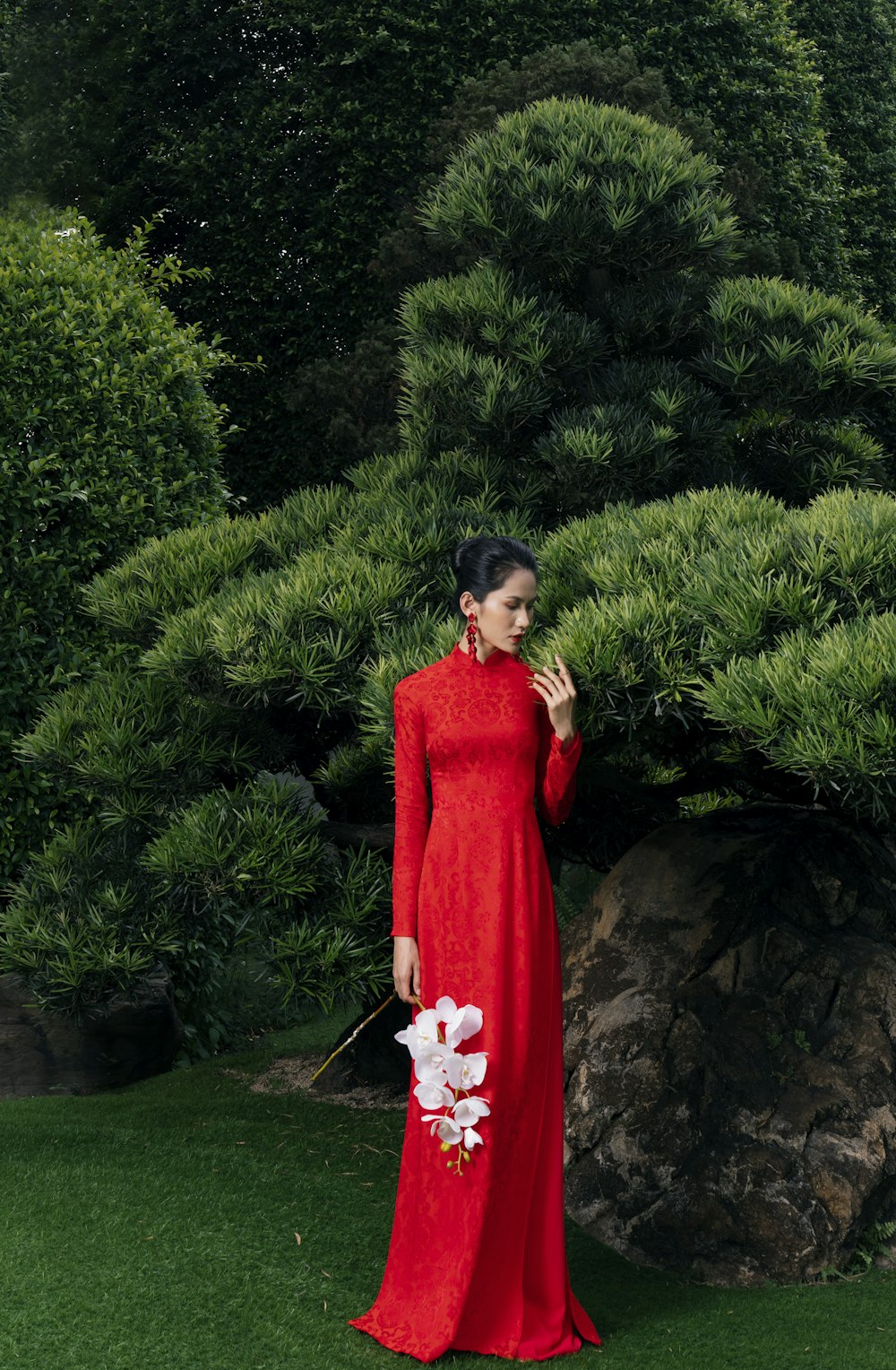 a woman in a red dress standing in front of a tree