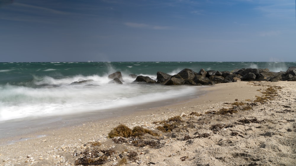 a sandy beach with a wave coming in to shore