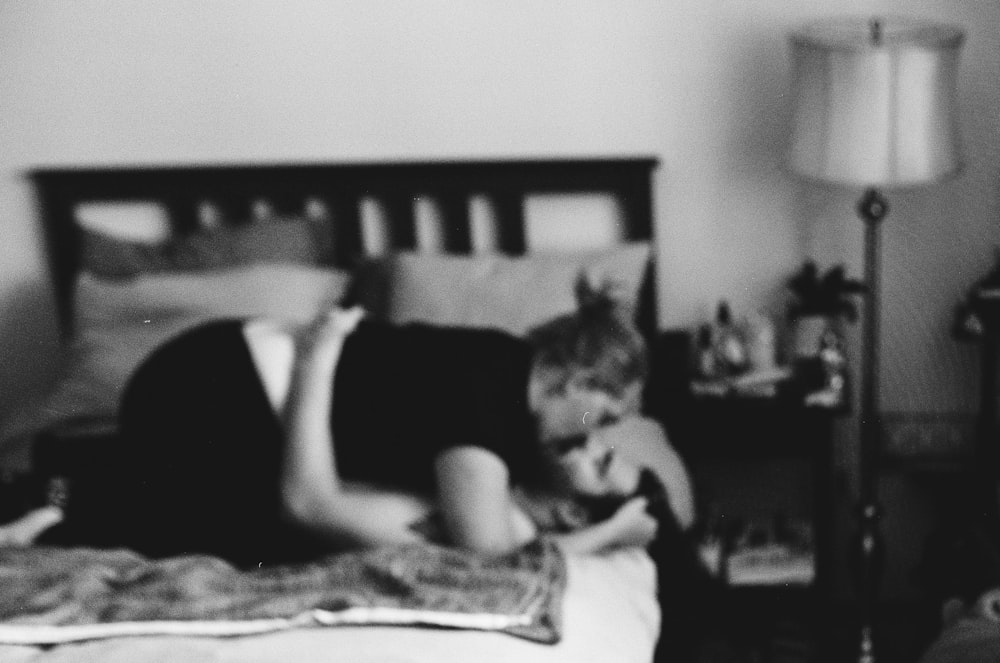 a black and white photo of a boy laying on a bed