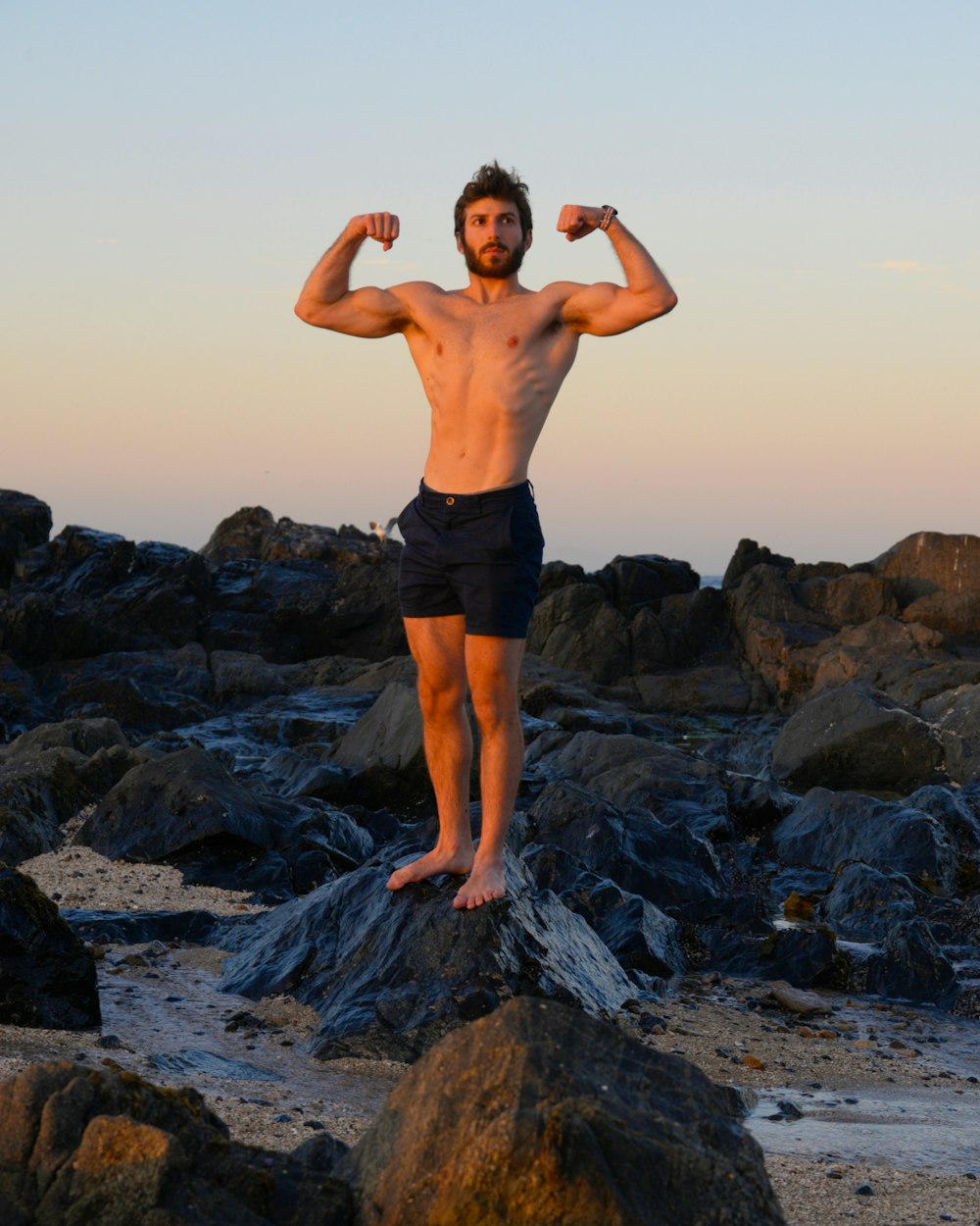 a man standing on top of a rock covered beach