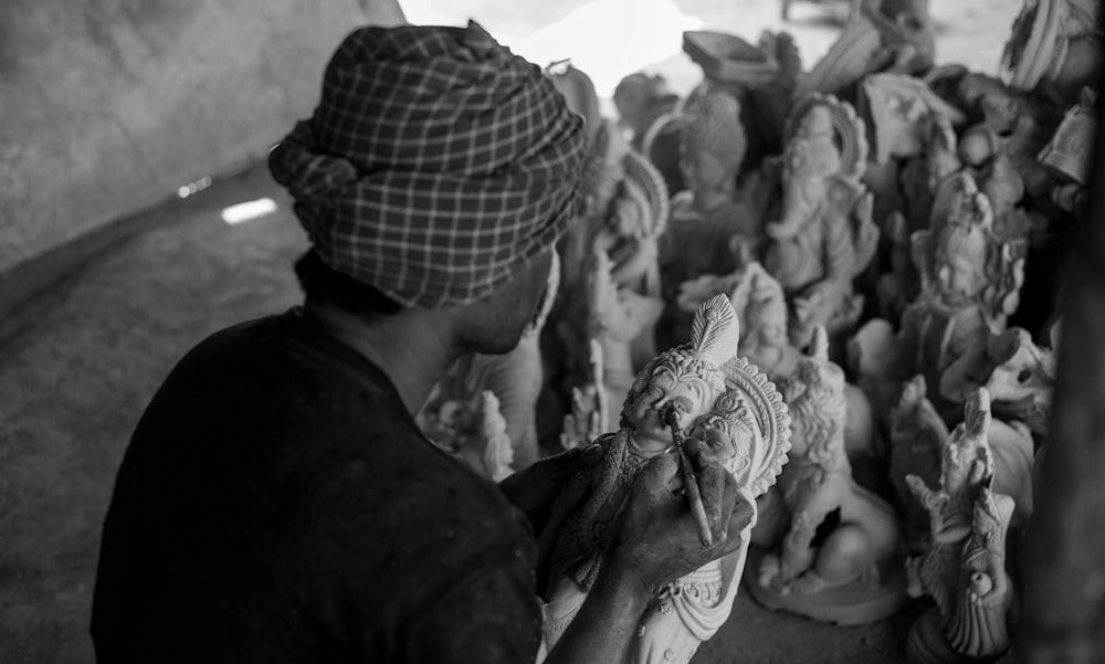 a black and white photo of a man working on a sculpture