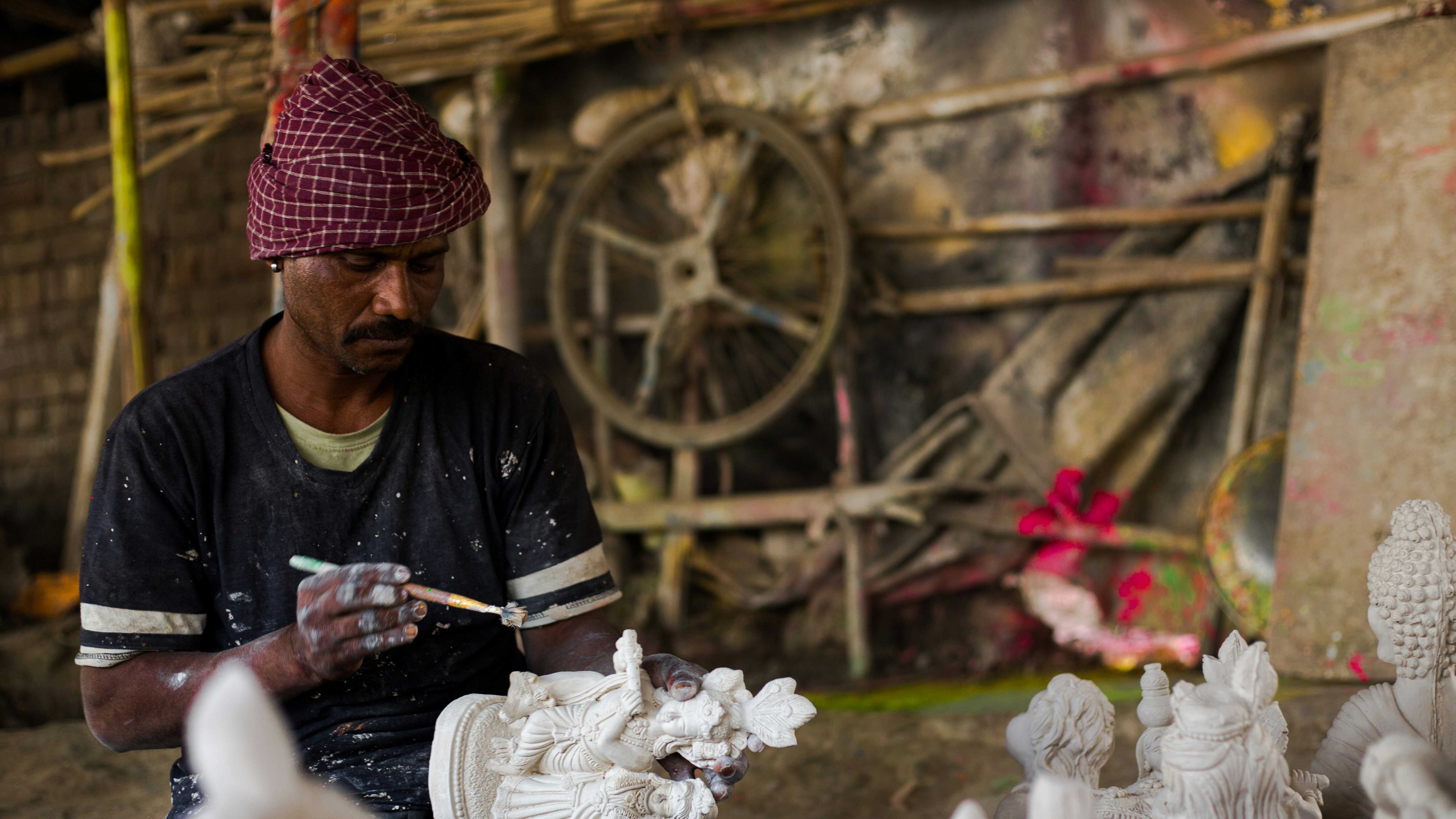 a man sitting in front of a group of white sculptures