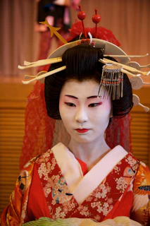 a geisha in a red kimono holding a plate of food