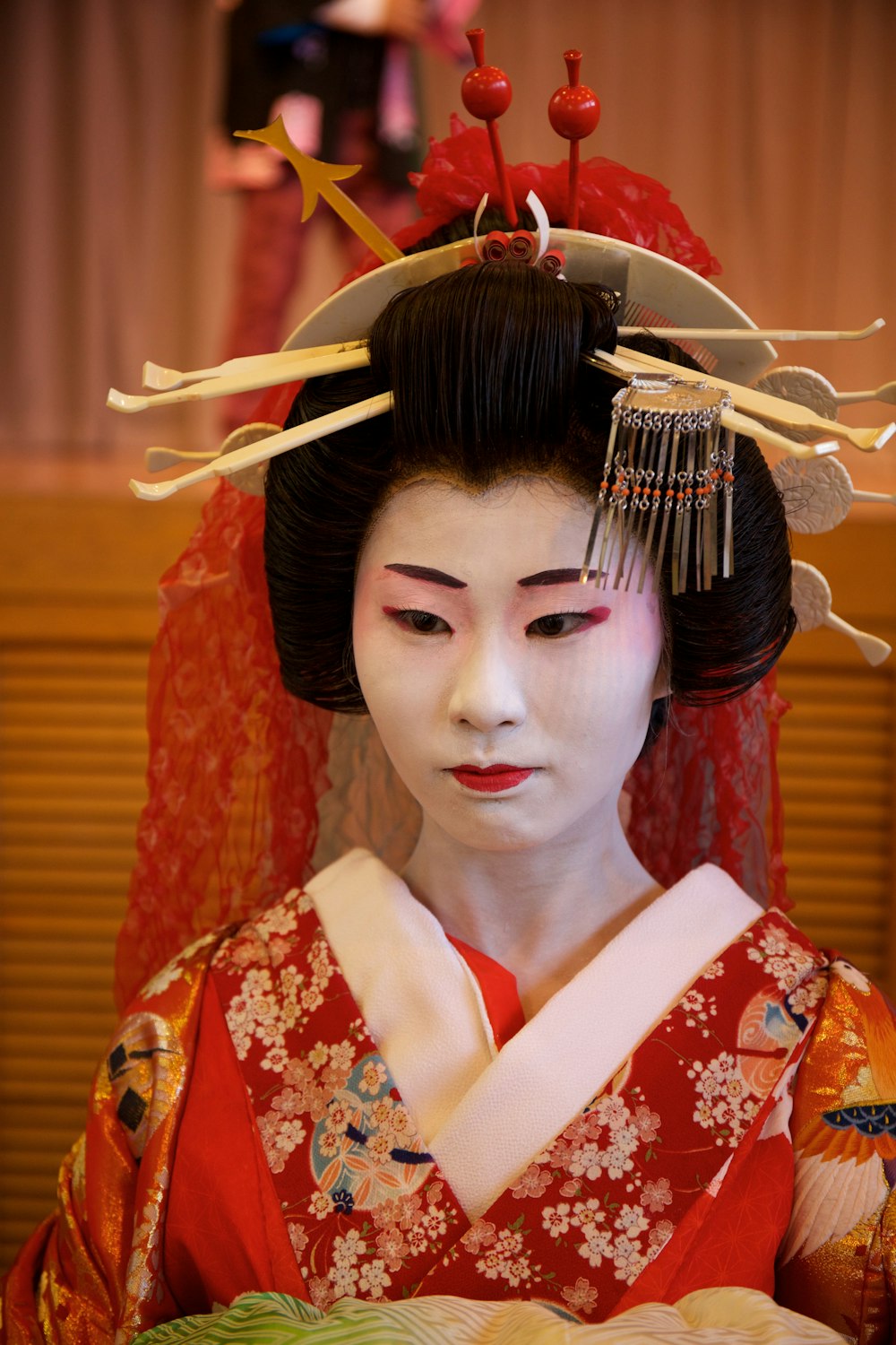 a geisha in a red kimono holding a plate of food