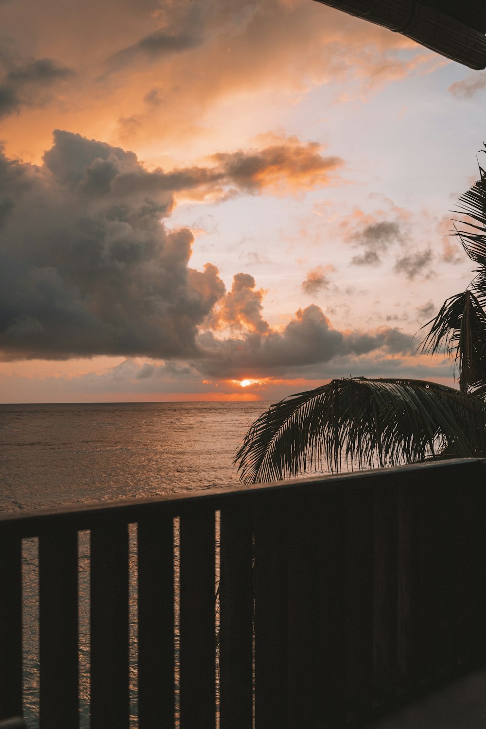 the sun is setting over the ocean from a balcony