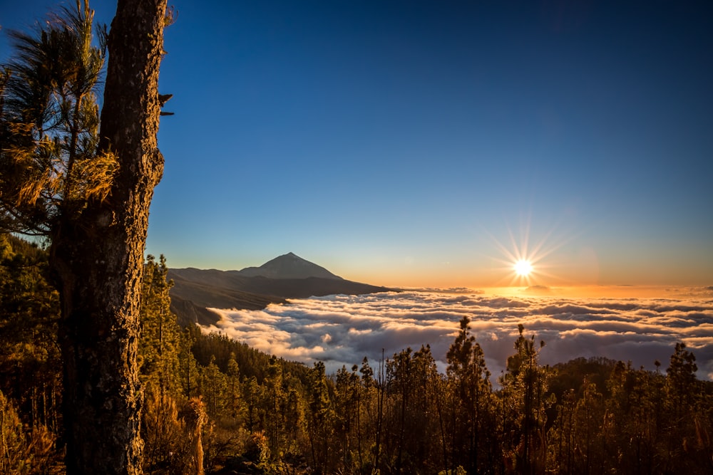 O sol está se pondo sobre as nuvens nas montanhas