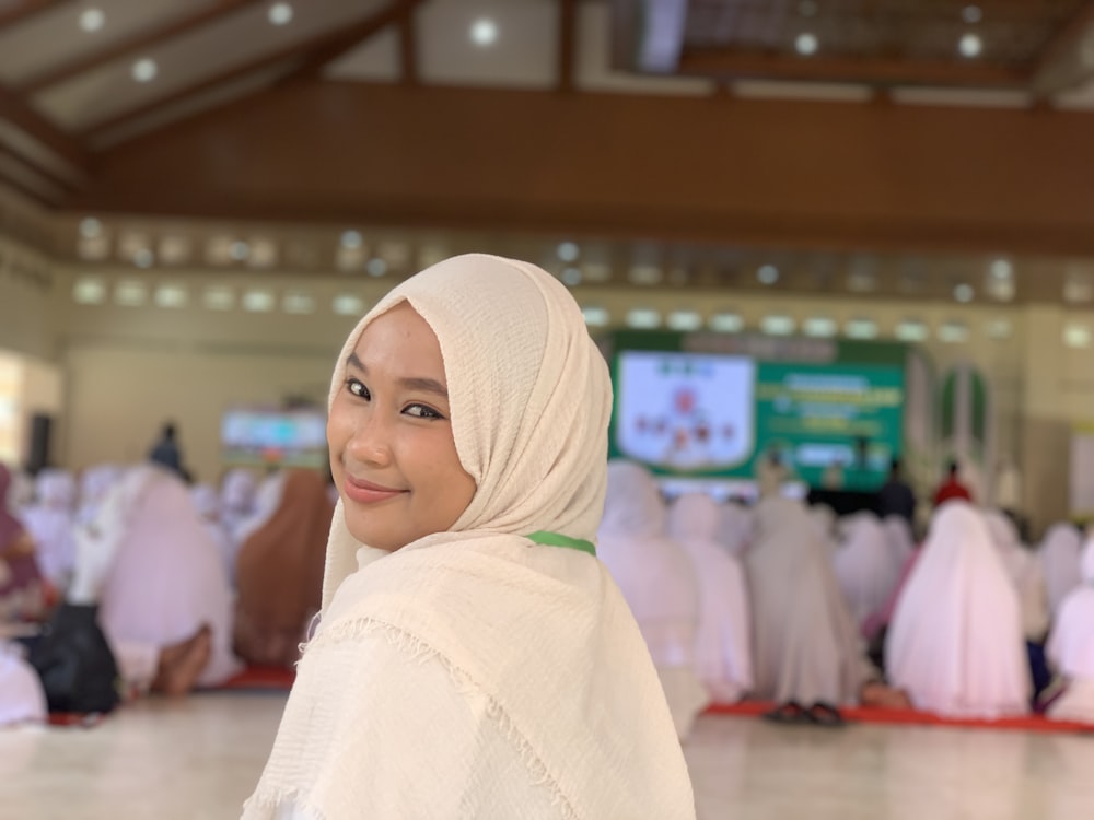 a woman in a hijab standing in front of a crowd of people