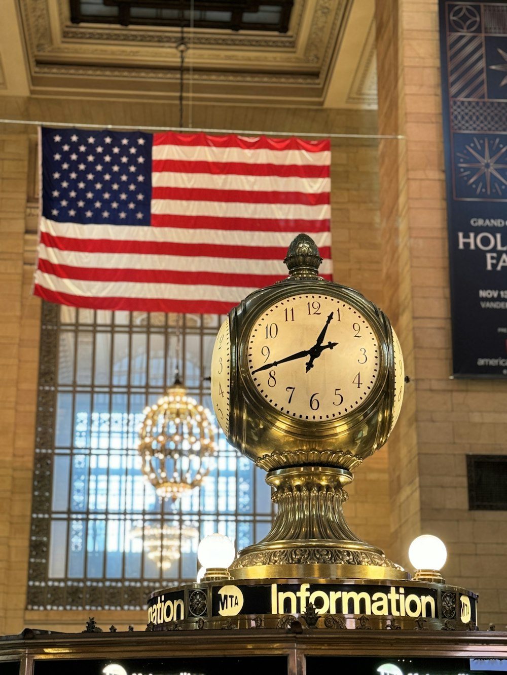a clock on top of a post in front of an american flag