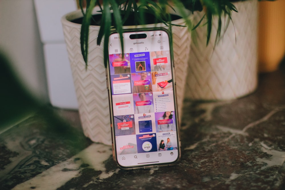 a cell phone sitting on top of a table next to a potted plant