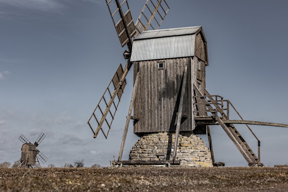 a wooden windmill sitting on top of a dry grass field