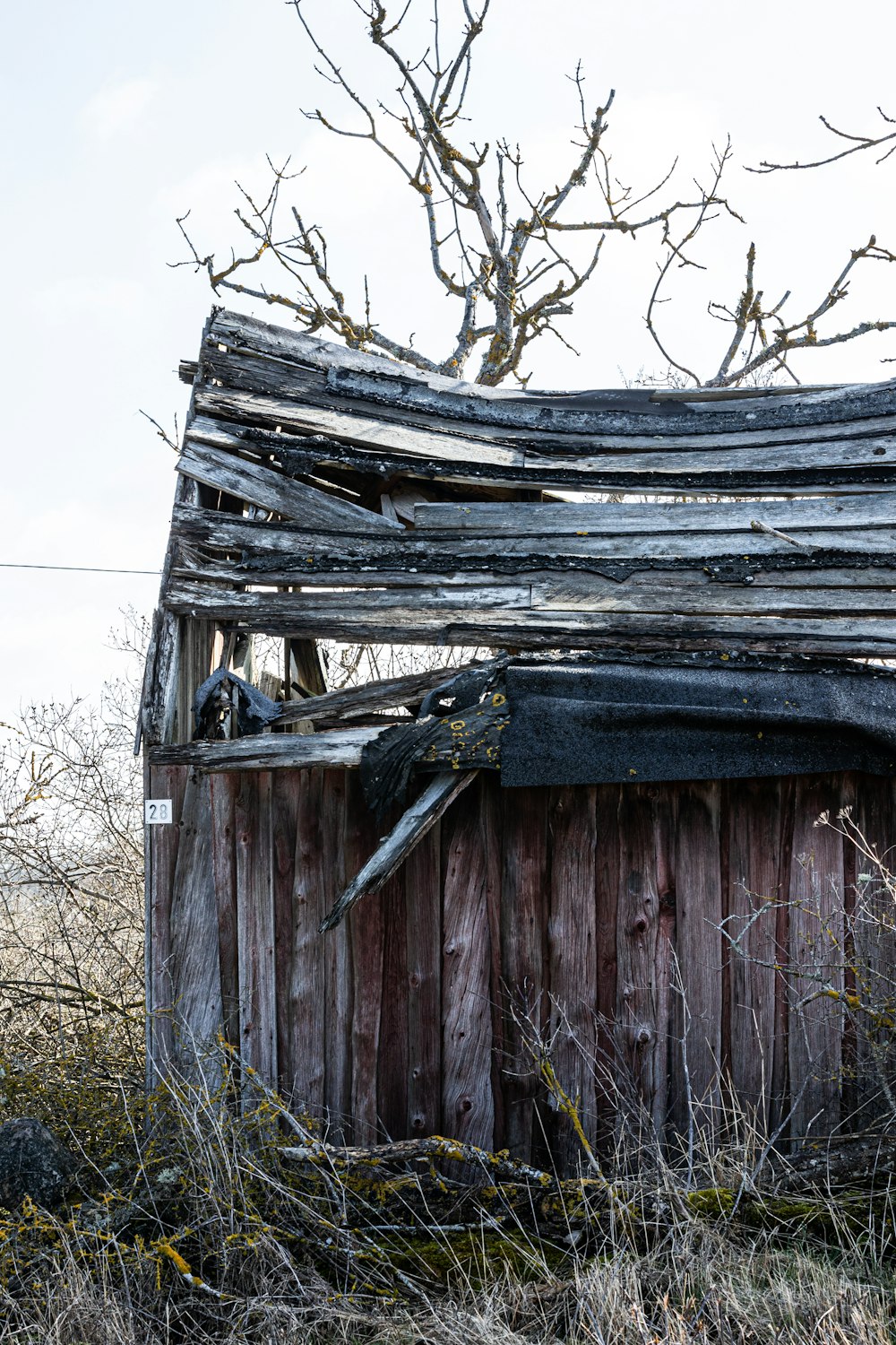 an old wooden shed with a broken roof