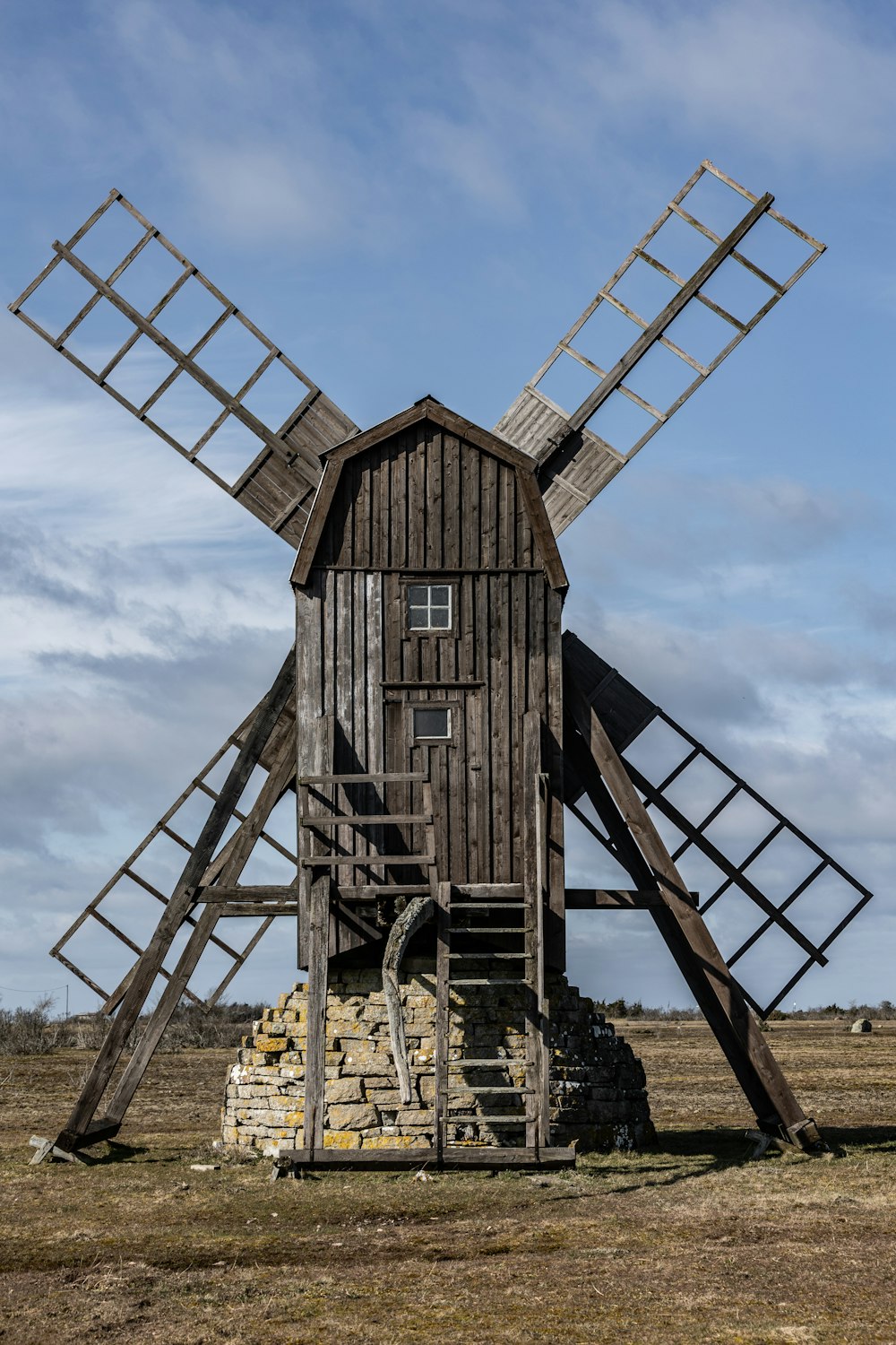 un molino de viento de madera sentado en medio de un campo