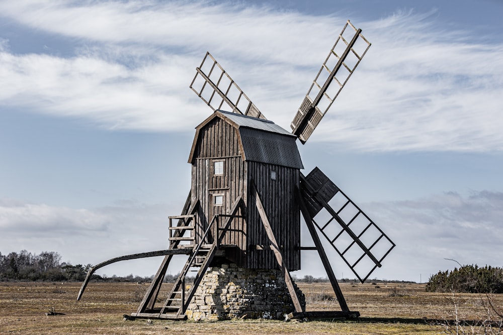 a wooden windmill sitting on top of a dry grass field