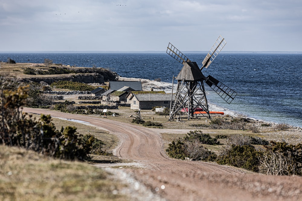 un moulin à vent assis sur le bord d’une route à côté de l’océan