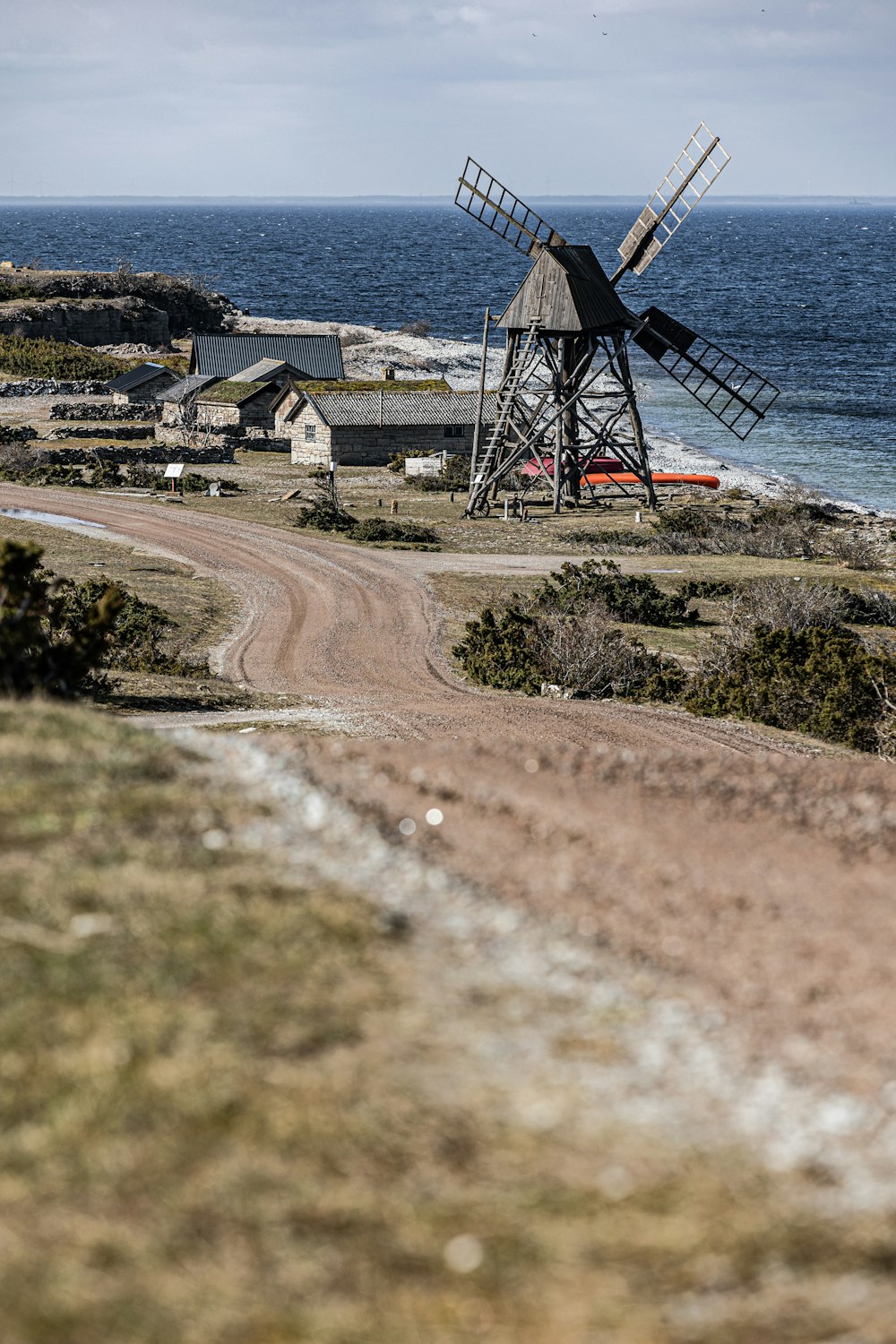 Un molino de viento al costado de un camino de tierra junto al océano