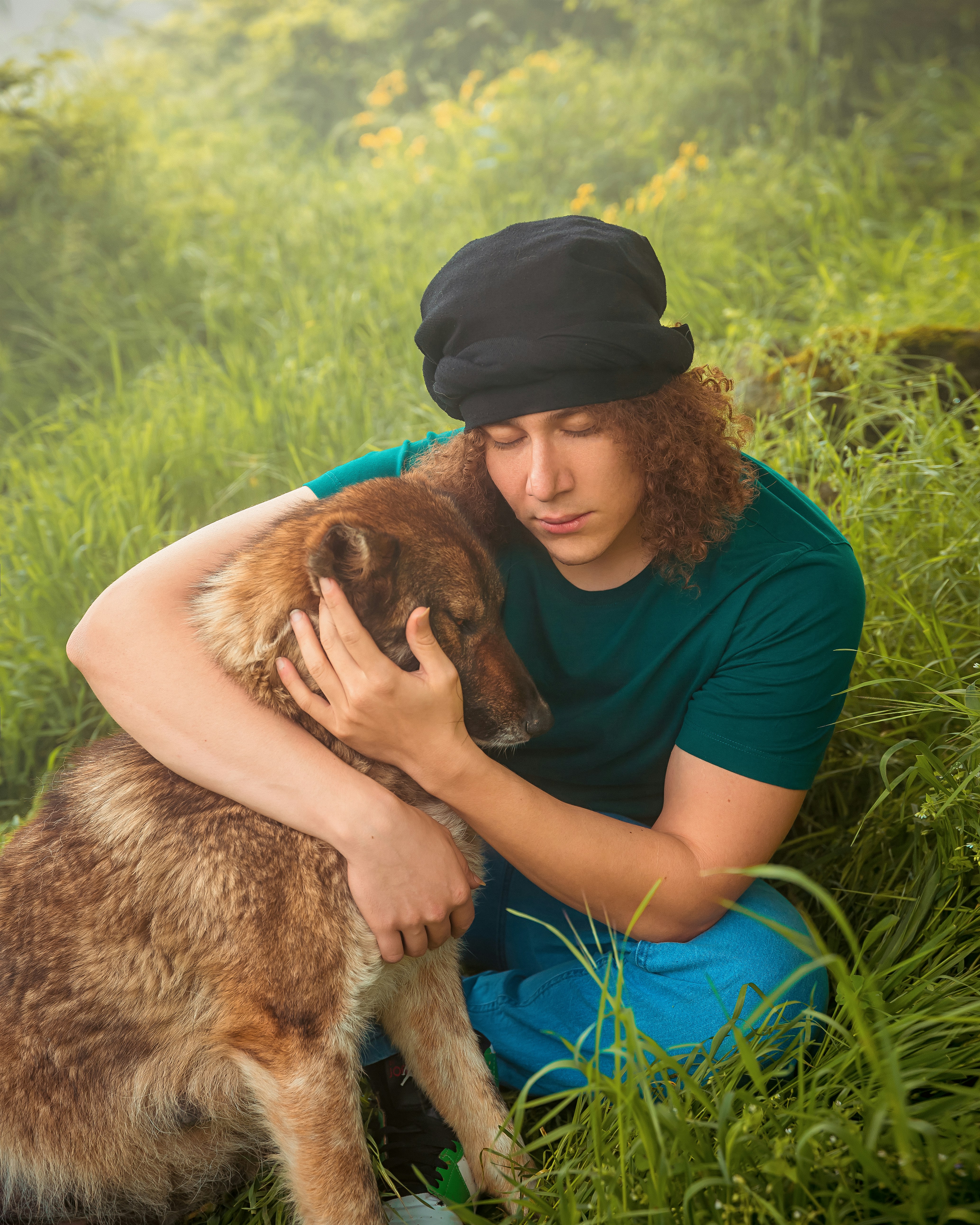 a man sitting in the grass with his dog